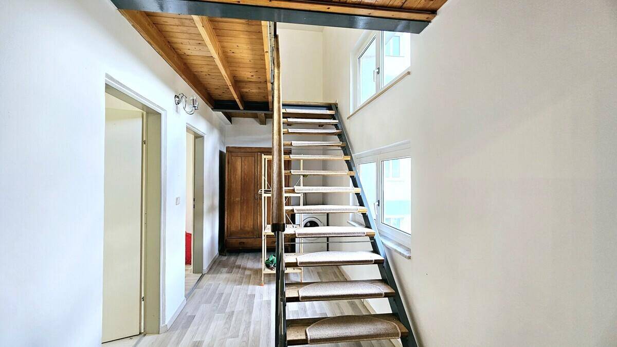 Moderne Treppe mit Metallrahmen und Holzstufen, die zu einem oberen Stockwerk führt.