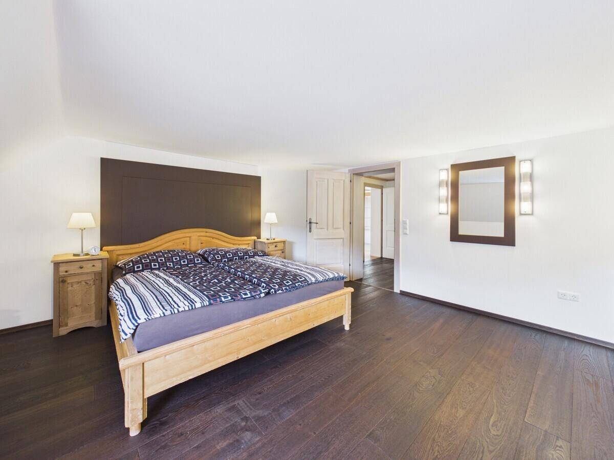 Geräumiges Schlafzimmer mit Holzbett, dunklem Holzboden und Zugang zu einem Ankleidezimmer.