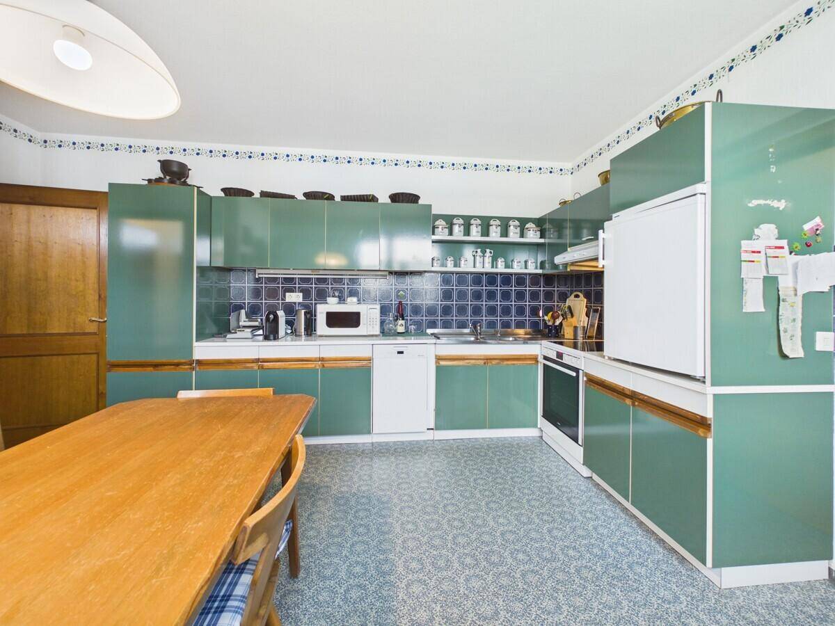 Küche im Vintage-Stil mit grünen Schränken, Essbereich und Fliesenboden.