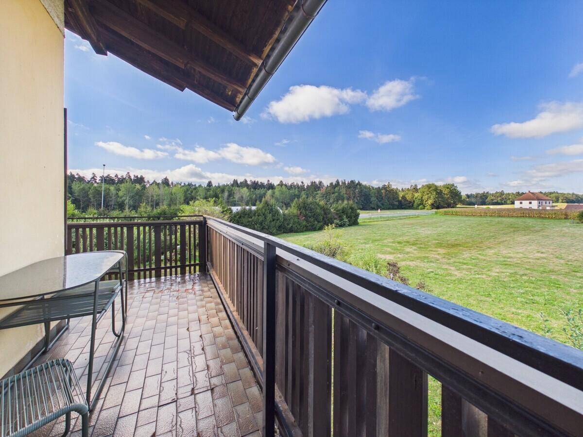 Balkon mit Fliesenboden und Geländer, bietet einen weiten Blick auf die grüne Landschaft.