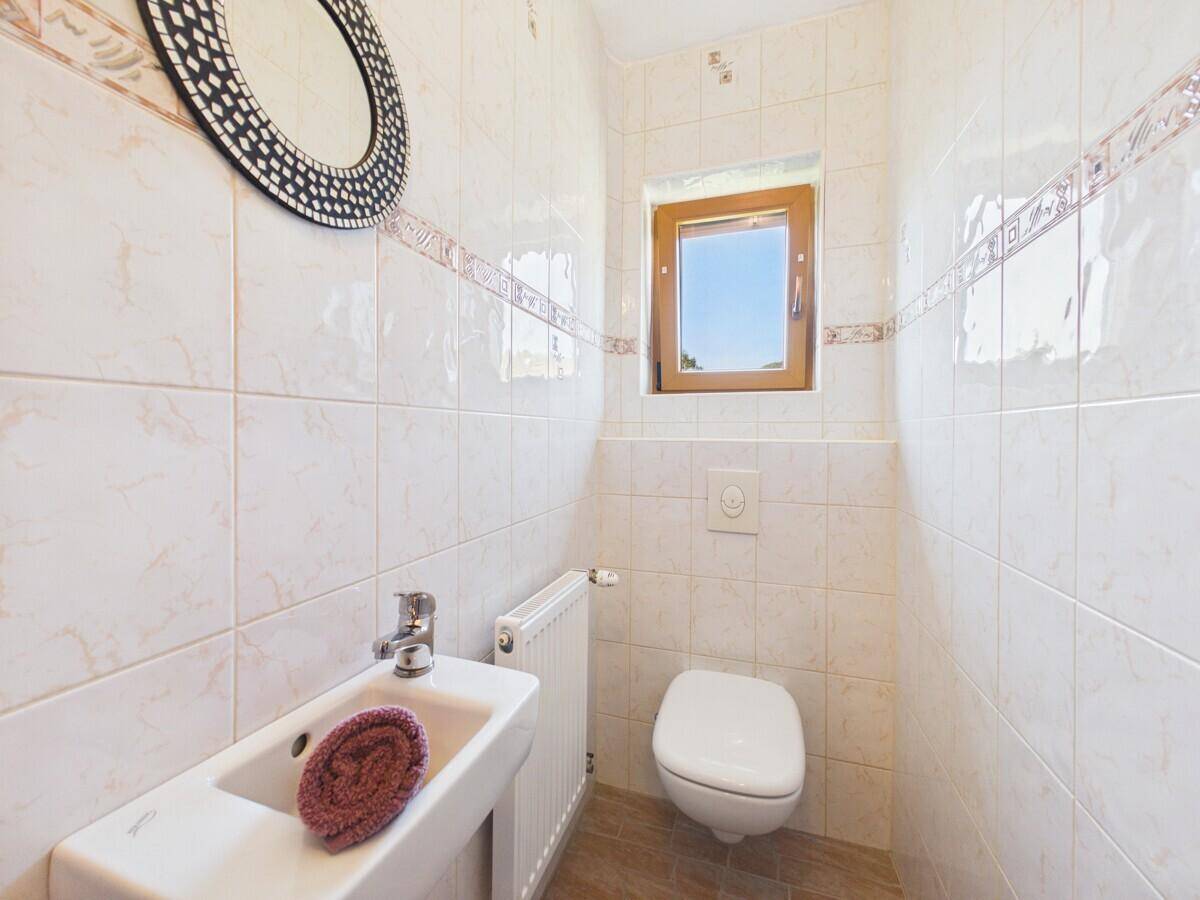 Funktionelles Gäste-WC mit Fenster, wandhängender Toilette und kleinem Handwaschbecken.