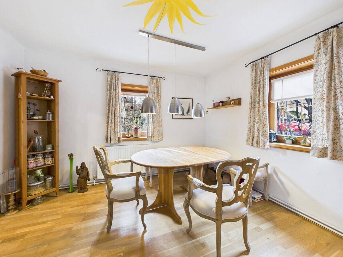 Gemütlicher Essbereich mit rundem Holztisch, klassischen Stühlen und Holzboden.