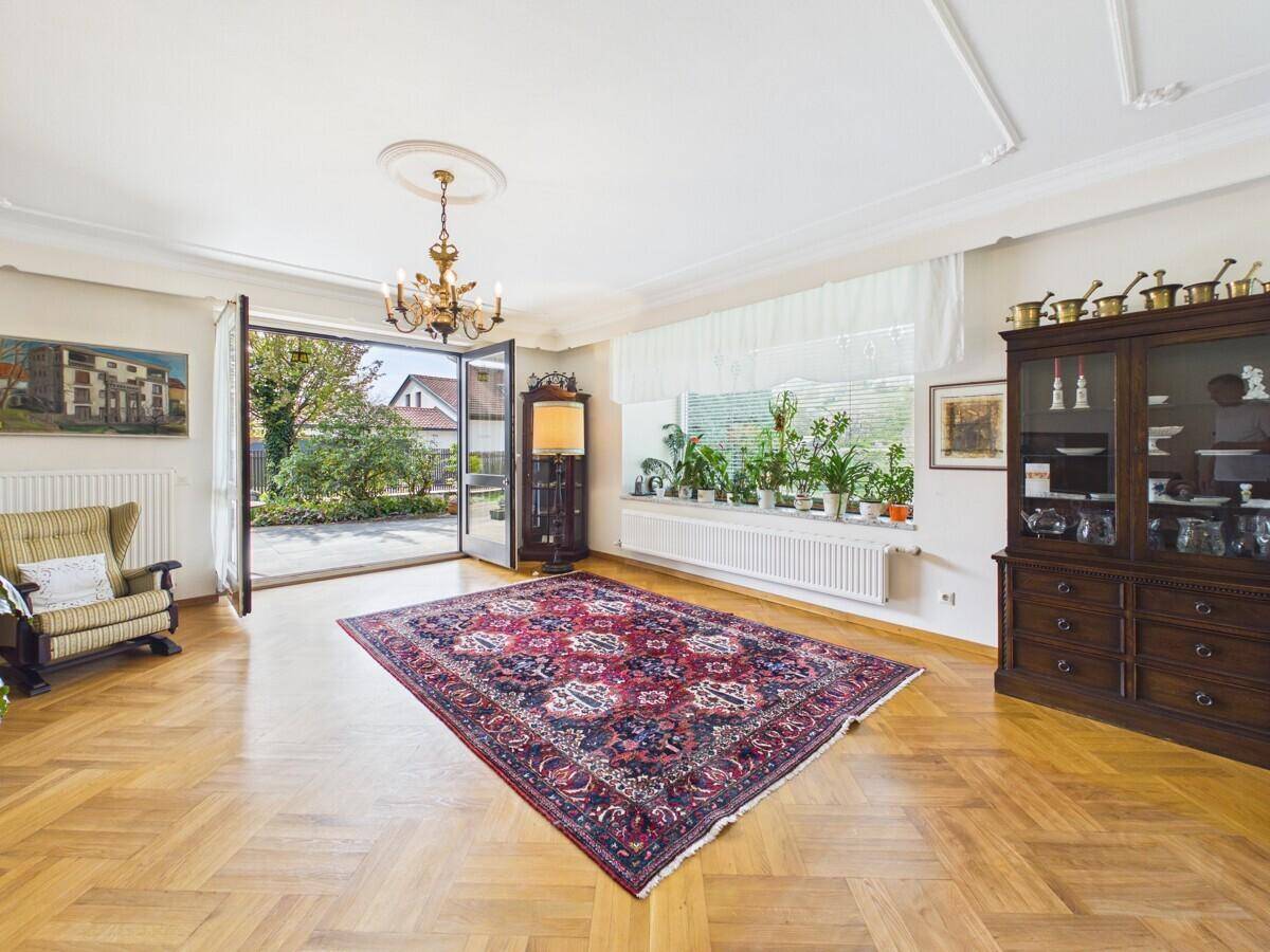 Helles Wohnzimmer mit Parkettboden, Stuckdecke und direktem Zugang zum Garten.
