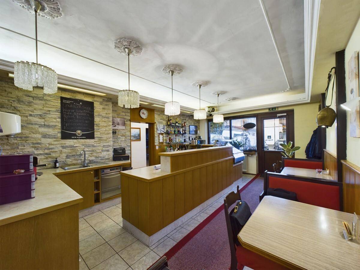 Bar- und Empfangsbereich mit Holztheke, Fliesenboden und Steinwandakzenten.