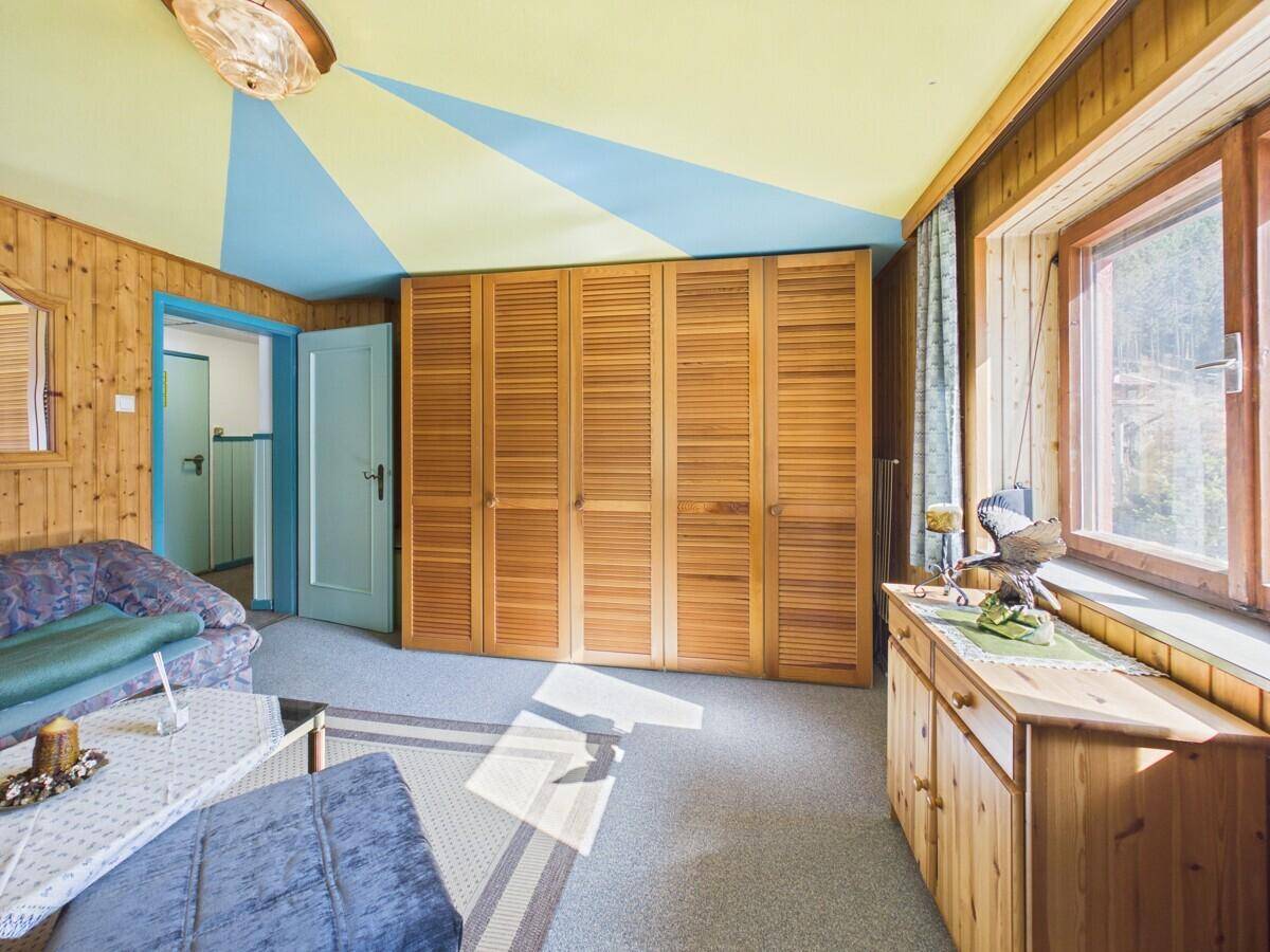 Schlafzimmer mit Holzvertäfelung, großen Einbauschränken und farbenfroher Decke.