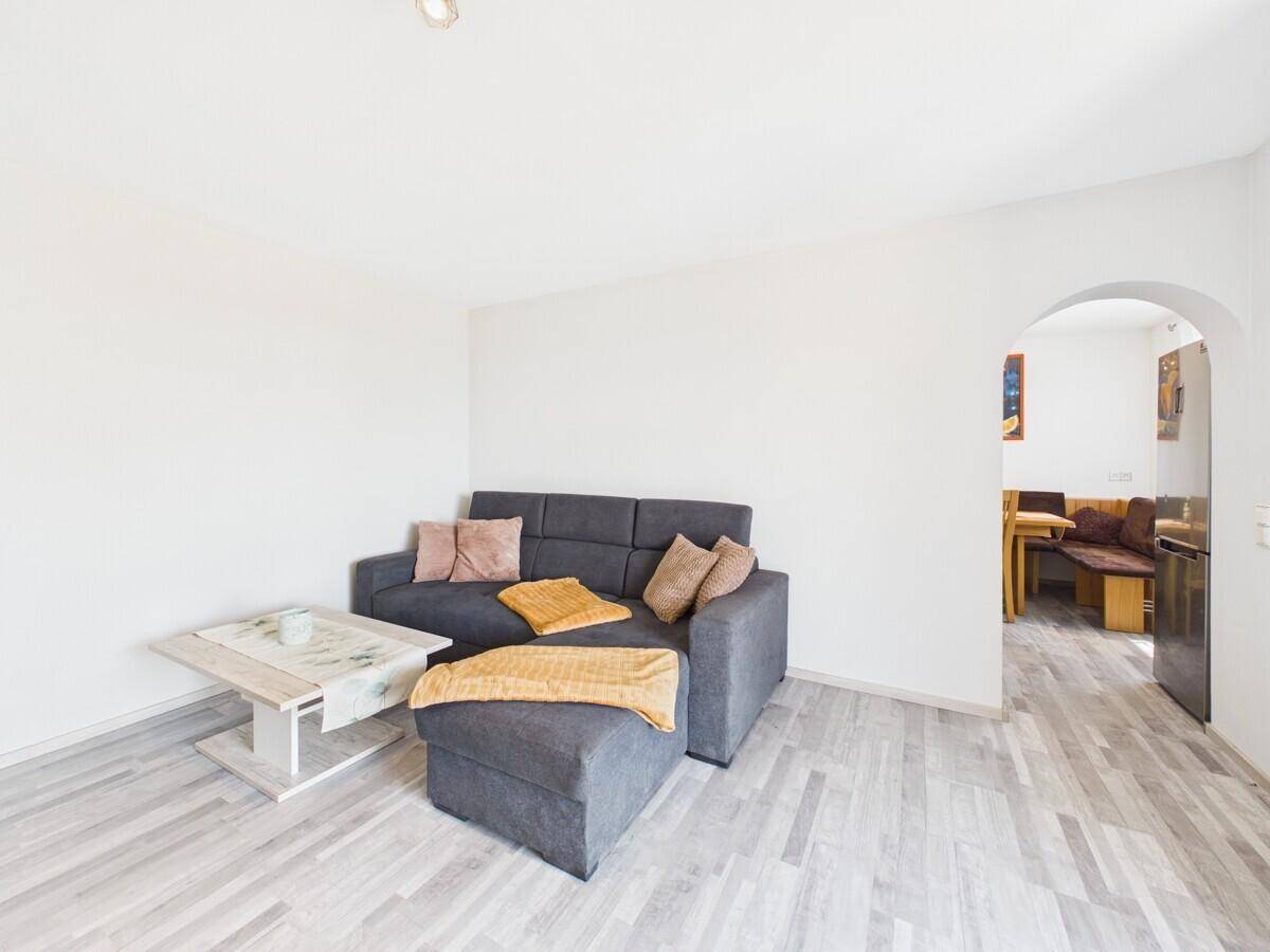 Helles Wohnzimmer mit bequemem Sofa und offenem Durchgang zu einem weiteren Raum.