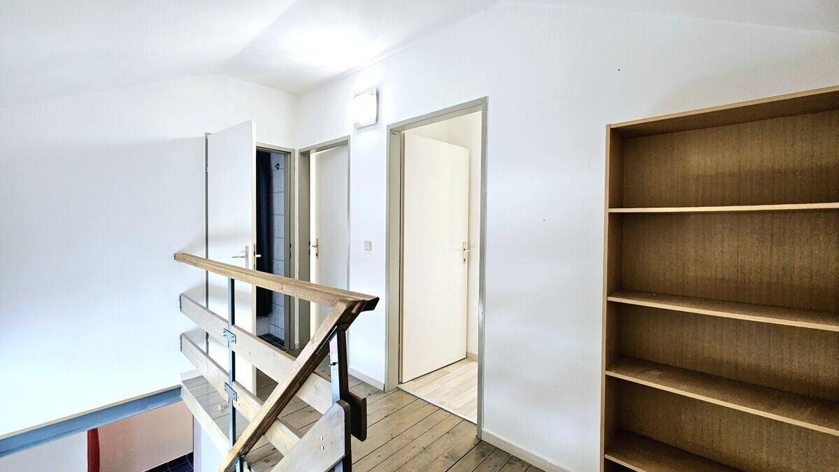 Geräumiger Flur mit Holzgeländer, Holzdielen und Zugang zu mehreren Zimmern.