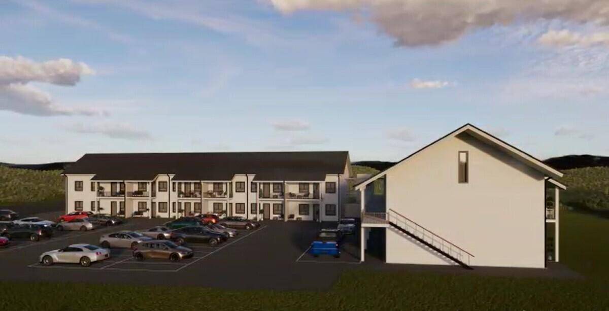 Moderne Wohnanlage mit mehreren Gebäuden und großem Parkplatz in ländlicher Umgebung.