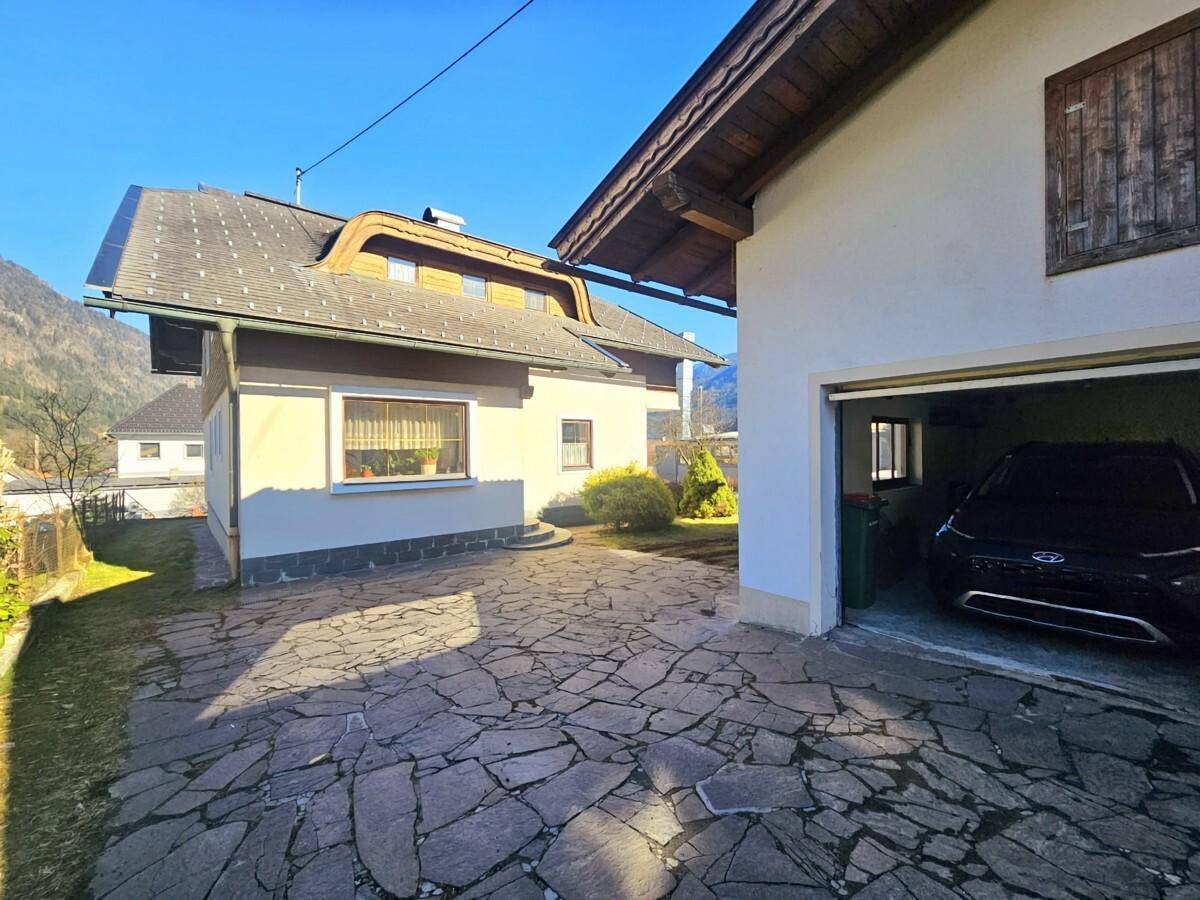 Zufahrt zum Haus mit Garage und gepflastertem Vorplatz.