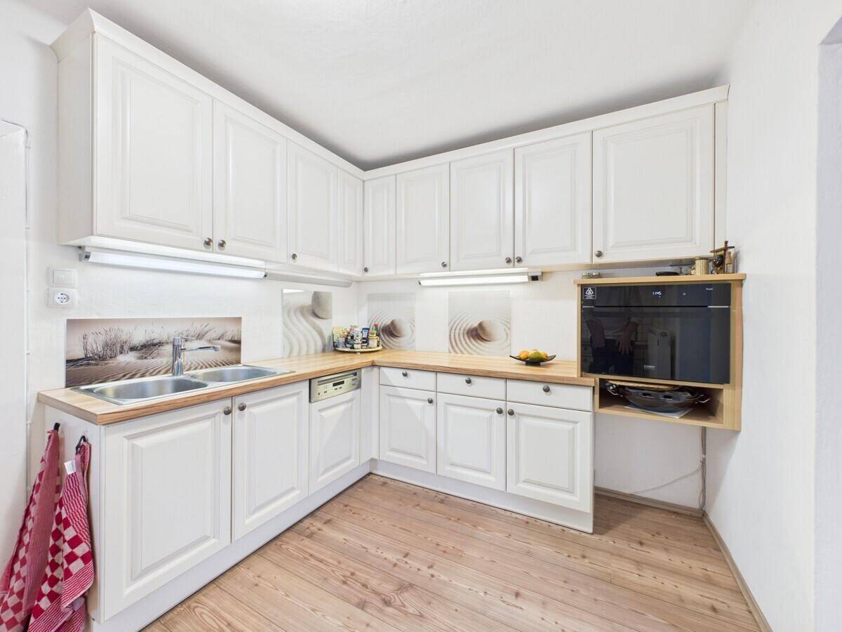 Helle Küche mit weißen Schränken, Holzarbeitsplatten und integriertem Backofen.