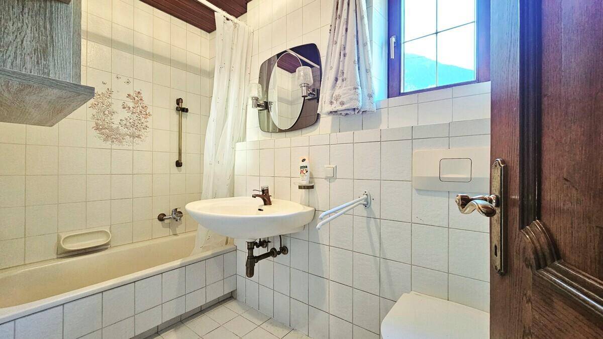 Badezimmer mit Badewanne, Waschbecken, WC und Fenster.