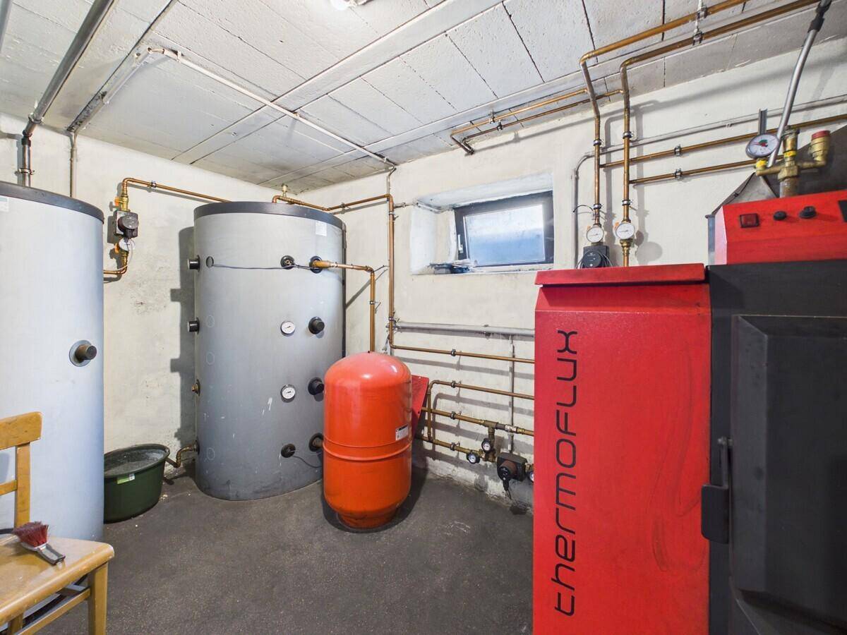 Heizungsraum im Keller mit großen Wassertanks und sichtbaren Rohrleitungen für die Wärmeversorgung.