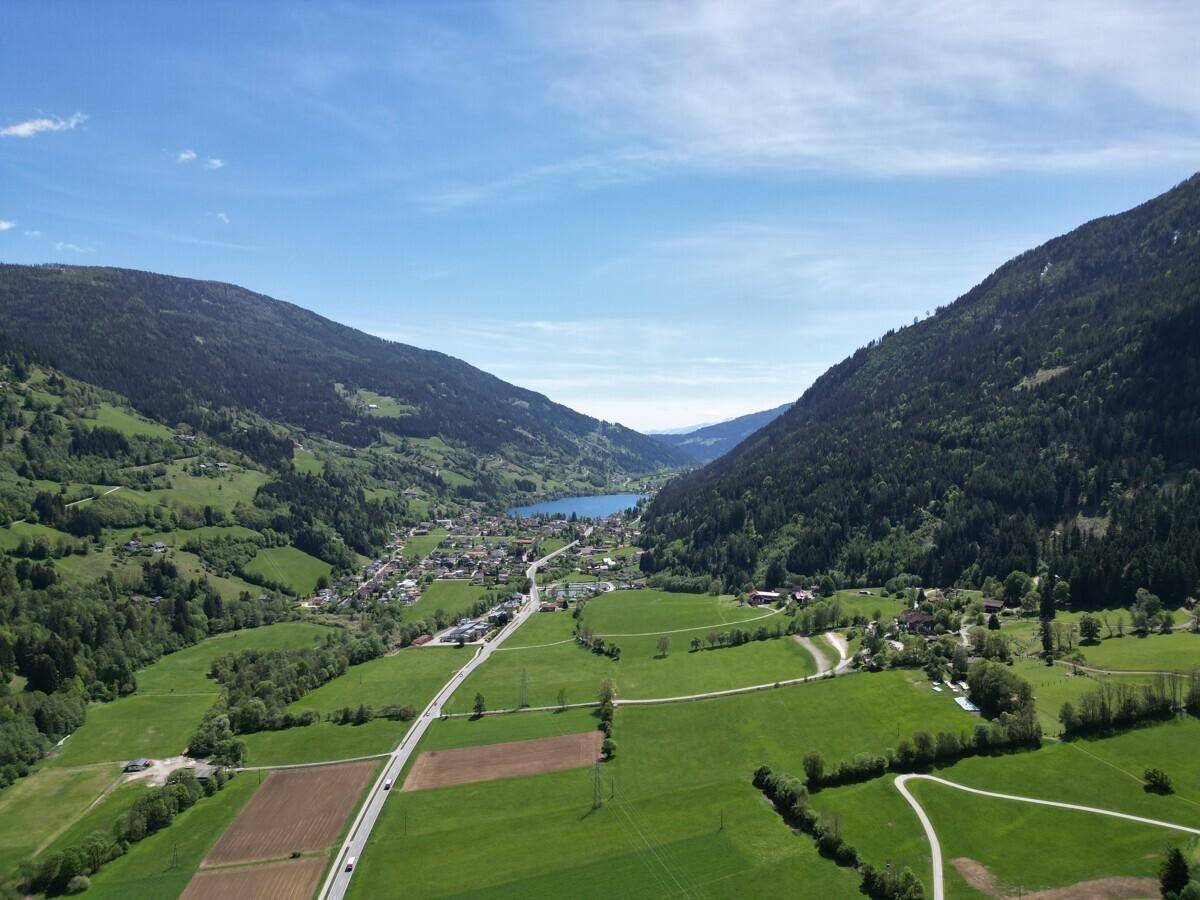 Panoramische Luftaufnahme eines Tals mit einem See, einer Straße und mehreren kleinen Ortschaften.