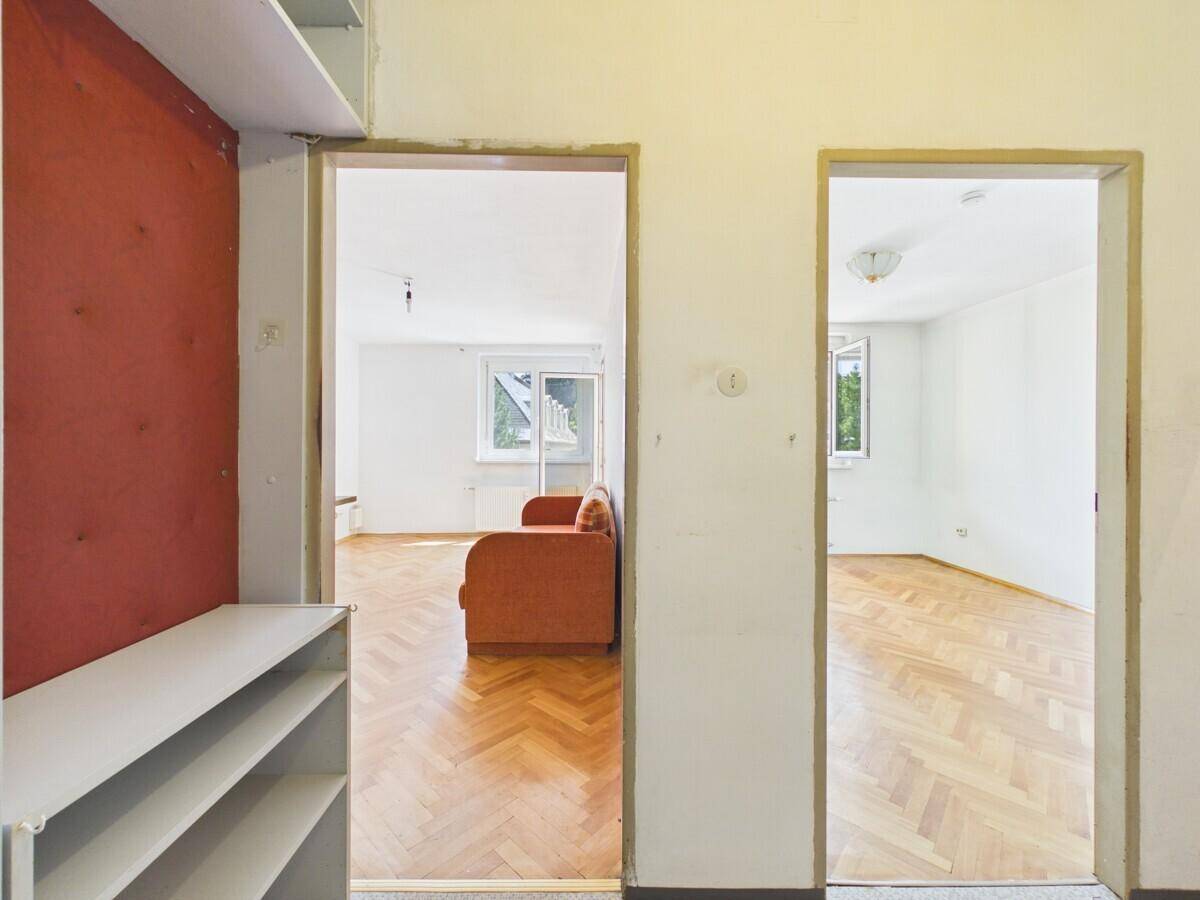 Flur mit Blick in zwei helle Zimmer, beide ausgestattet mit Fischgrätparkett.