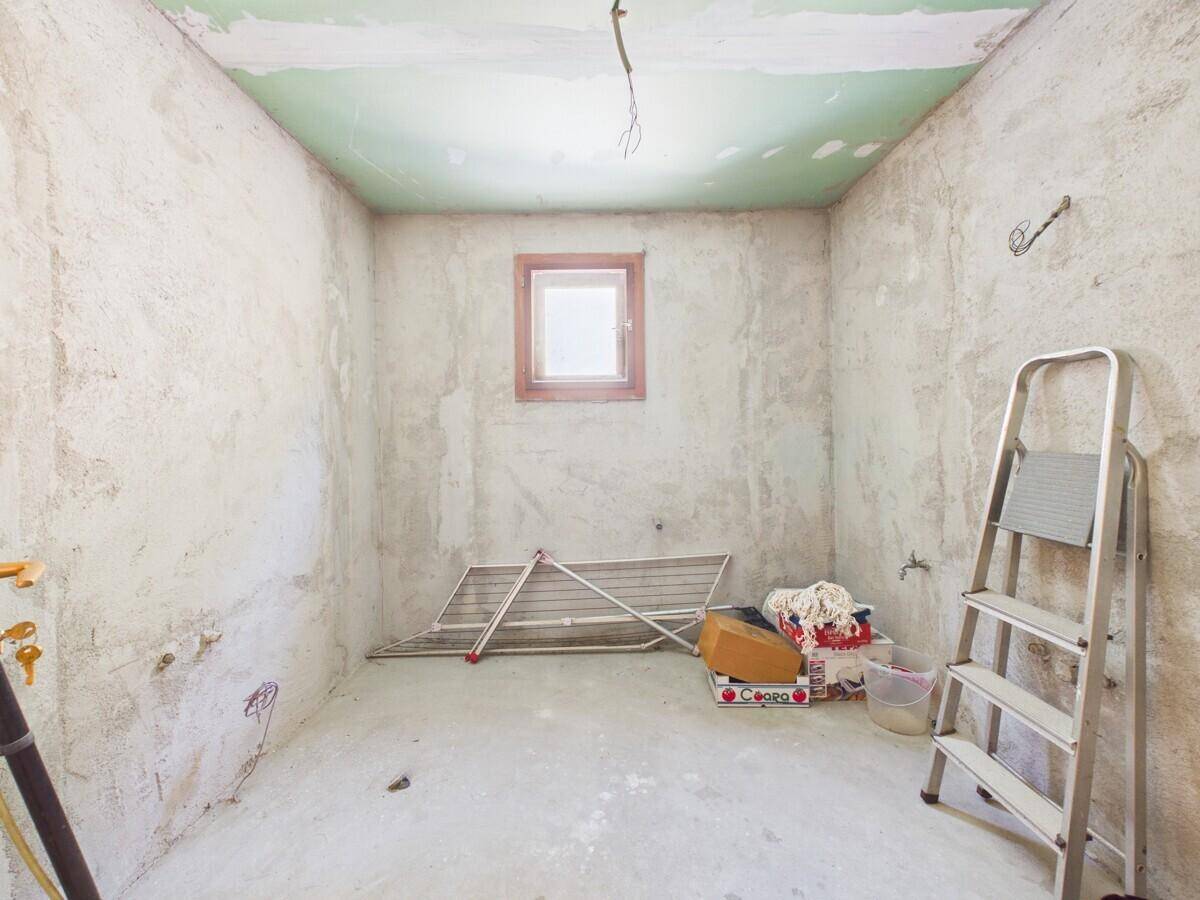 Unfertiger Raum mit Fenster, bereit für Renovierung oder als einfacher Abstellraum nutzbar.