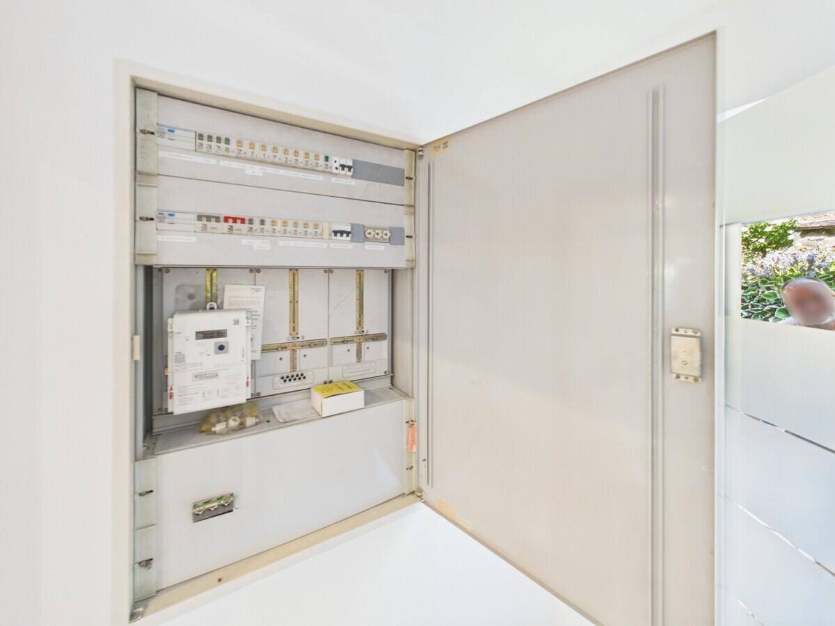 Offener Sicherungskasten mit Stromzähler und elektrischen Installationen in einem Versorgungsbereich.