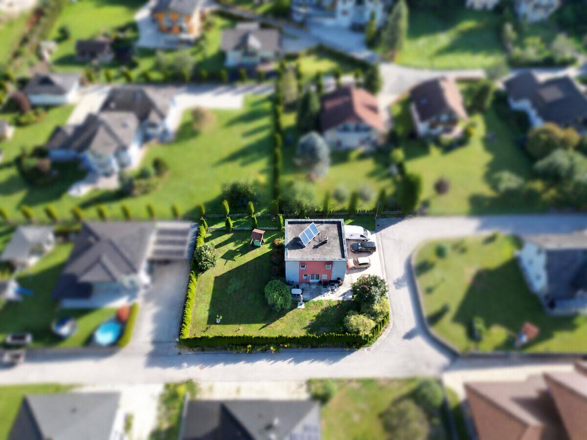 Luftaufnahme des Hauses mit gepflegtem Garten, Photovoltaikanlage und Stellplätzen.