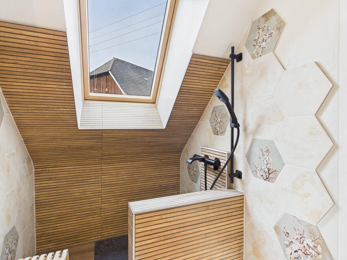 Modernes Badezimmer mit Dusche, Holzverkleidung und einem Dachfenster für viel Licht.