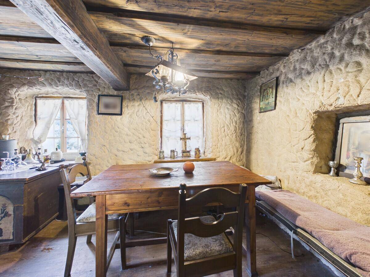 Rustikaler Essbereich mit Holztisch, Steinwänden und sichtbaren Deckenbalken.