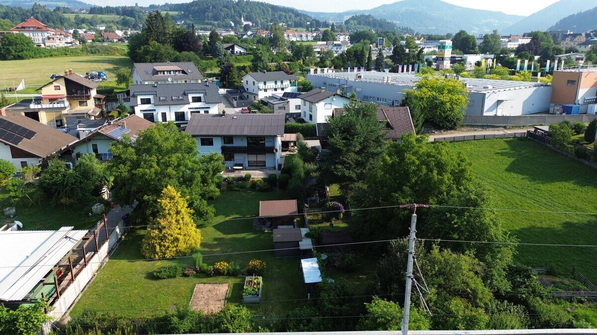 Weitläufige Luftaufnahme der Wohnsiedlung mit viel Grün und Blick auf die umliegende Landschaft.
