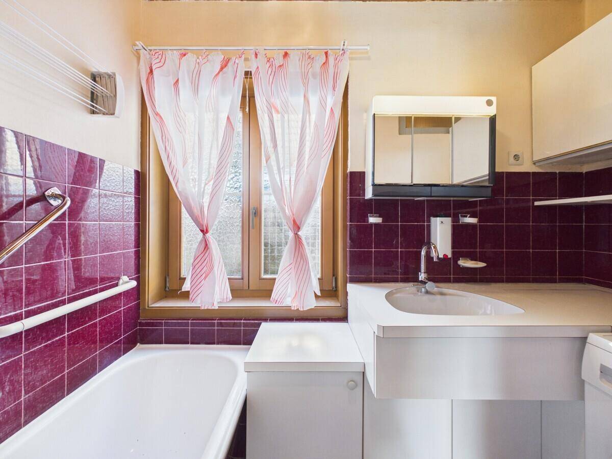 Badezimmer mit Badewanne, Waschbecken und roten Fliesen im Vintage-Stil der 80er Jahre.