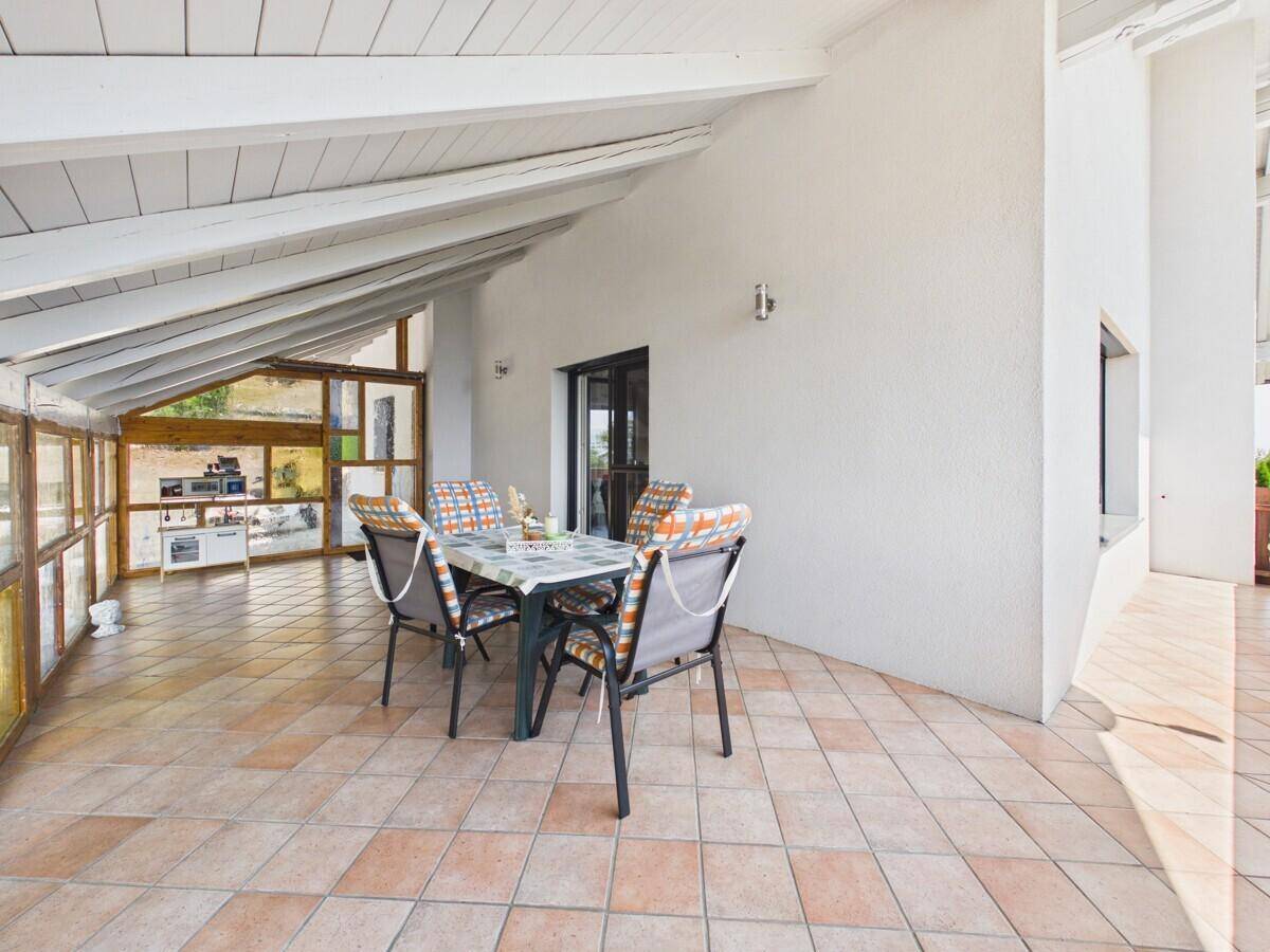 Überdachte Terrasse mit Essbereich und Fliesenboden, ideal für entspannte Stunden im Freien.