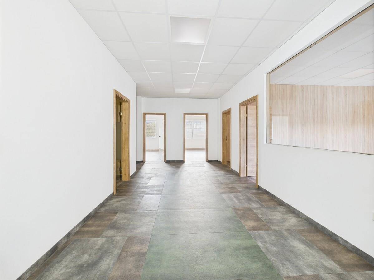Geräumiger Flur mit mehreren Holztüren und dunklen Fliesen, führt zu weiteren Räumen.