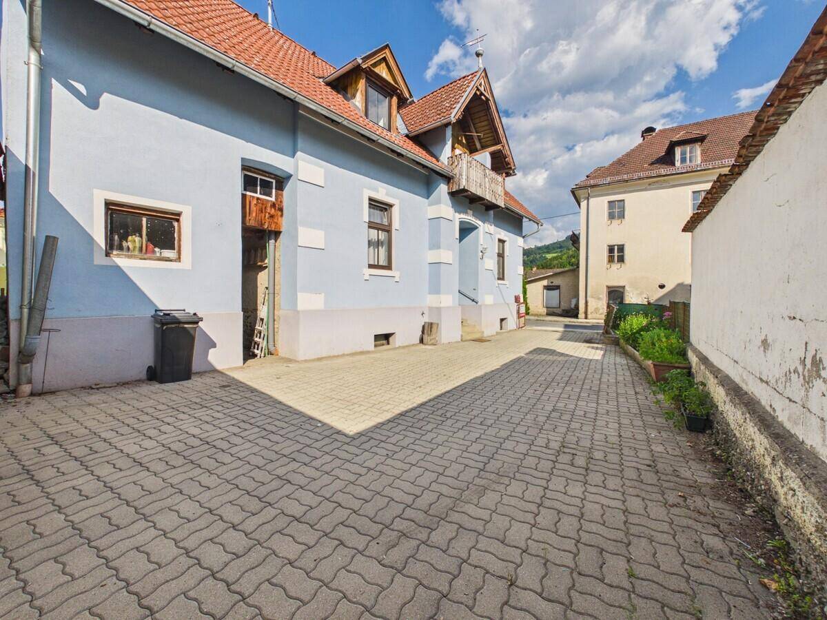 Außenbereich des Hauses mit gepflasterter Fläche und Blick auf die Nachbargebäude.