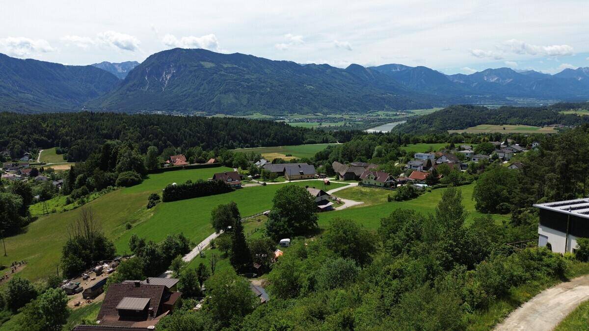 Panoramablick über ein grünes Tal mit einem Fluss in der Ferne, umgeben von Wäldern und Bergen.