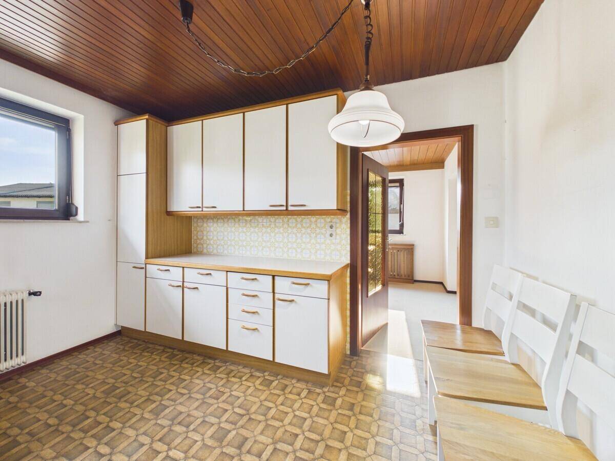 Geräumige Küche mit Holzdecke, weißen Einbauschränken und Platz für einen Essbereich.