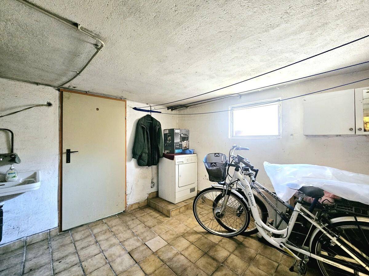 Waschküche im Keller mit Waschmaschine, Trockner und Fenster.