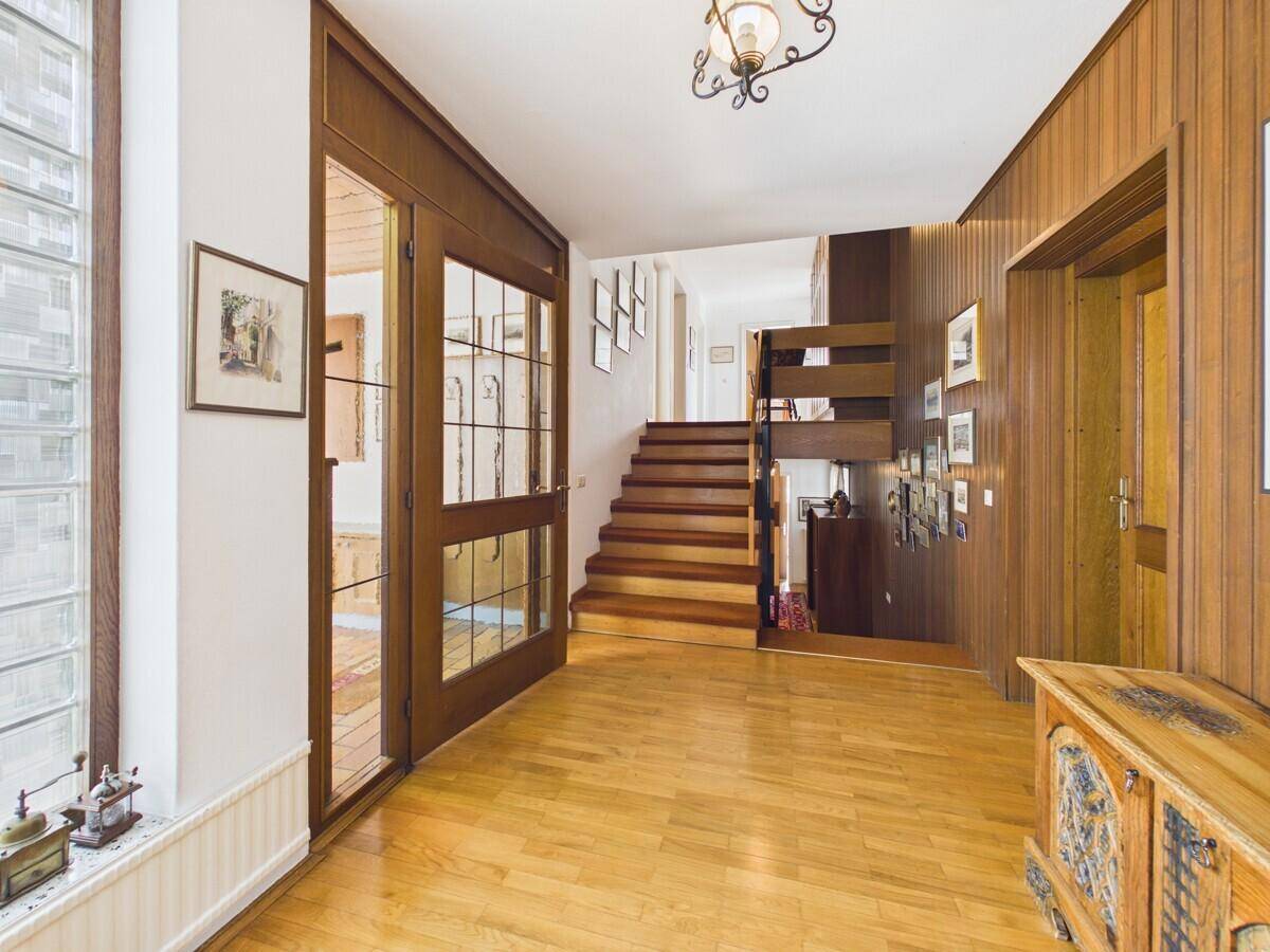 Geräumiger Flur mit Holztreppe, Parkettboden und Holzvertäfelung an den Wänden.
