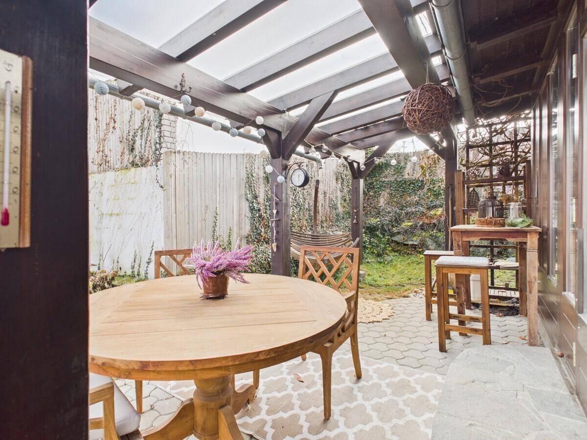 Überdachte Terrasse mit Holzdach, Esstisch und gemütlicher Beleuchtung im Garten.