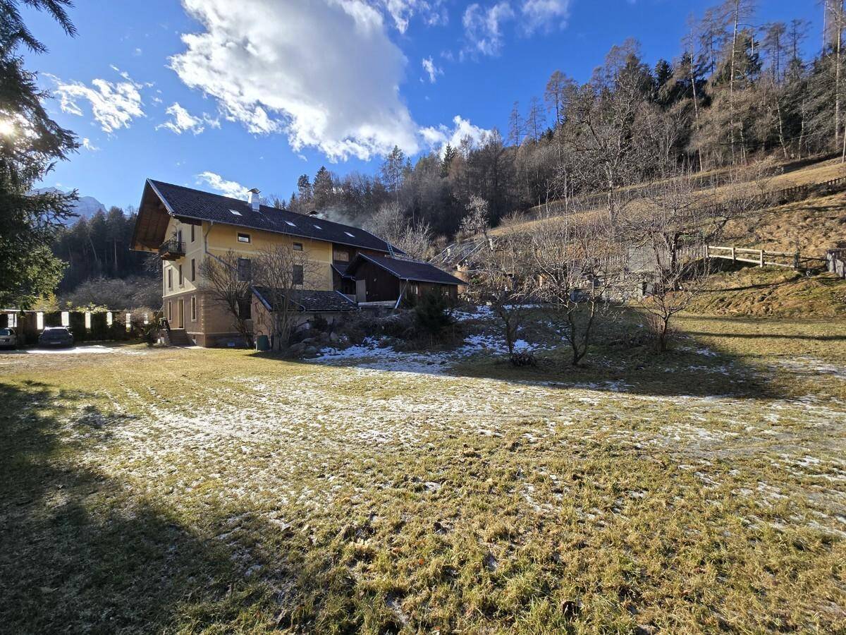 Weitläufiger Gartenbereich mit leichter Schneedecke und Blick auf die umliegende Berglandschaft.