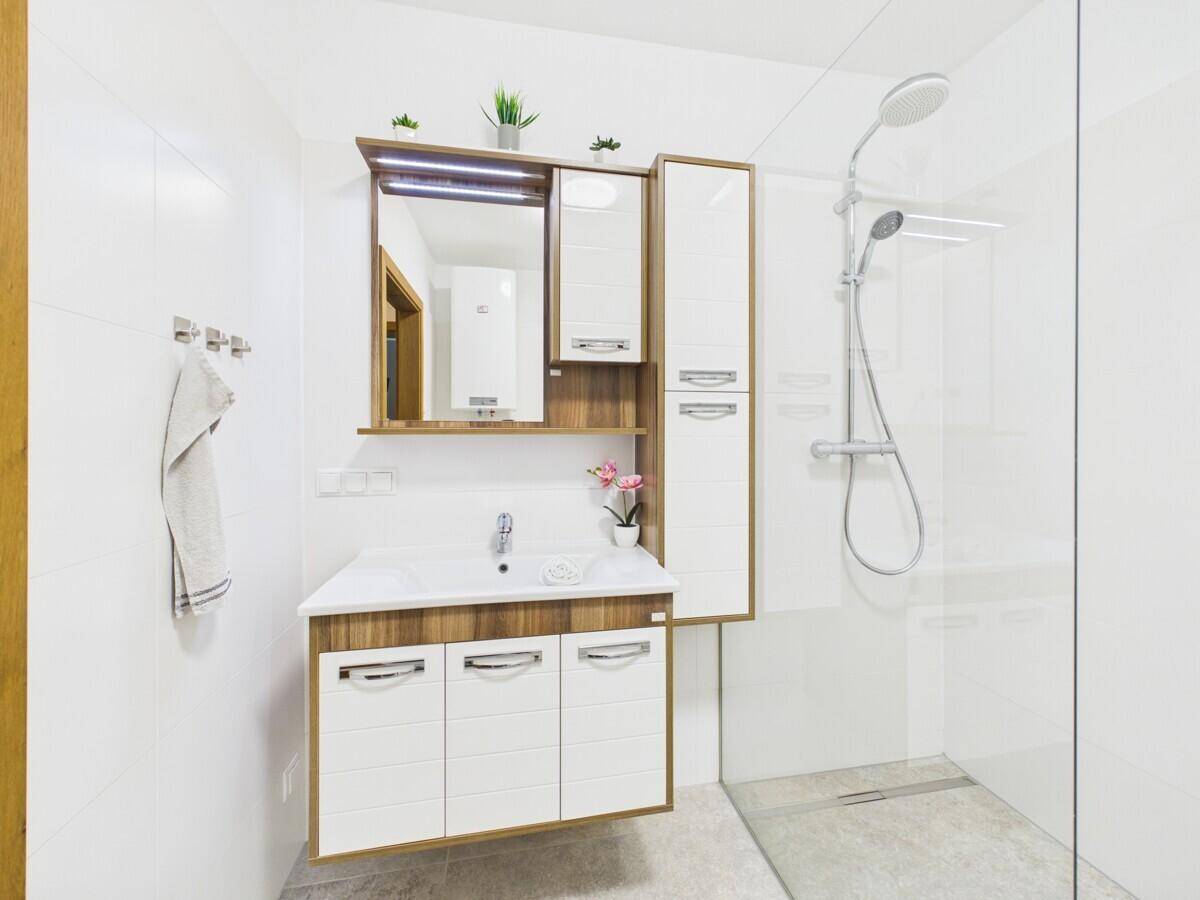 Modernes Badezimmer mit Waschtisch, Spiegelschrank und begehbarer Dusche.