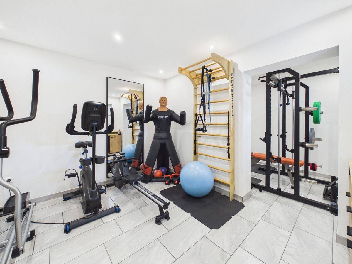 Gut ausgestatteter Fitnessraum mit verschiedenen Trainingsgeräten und Sprossenwand.