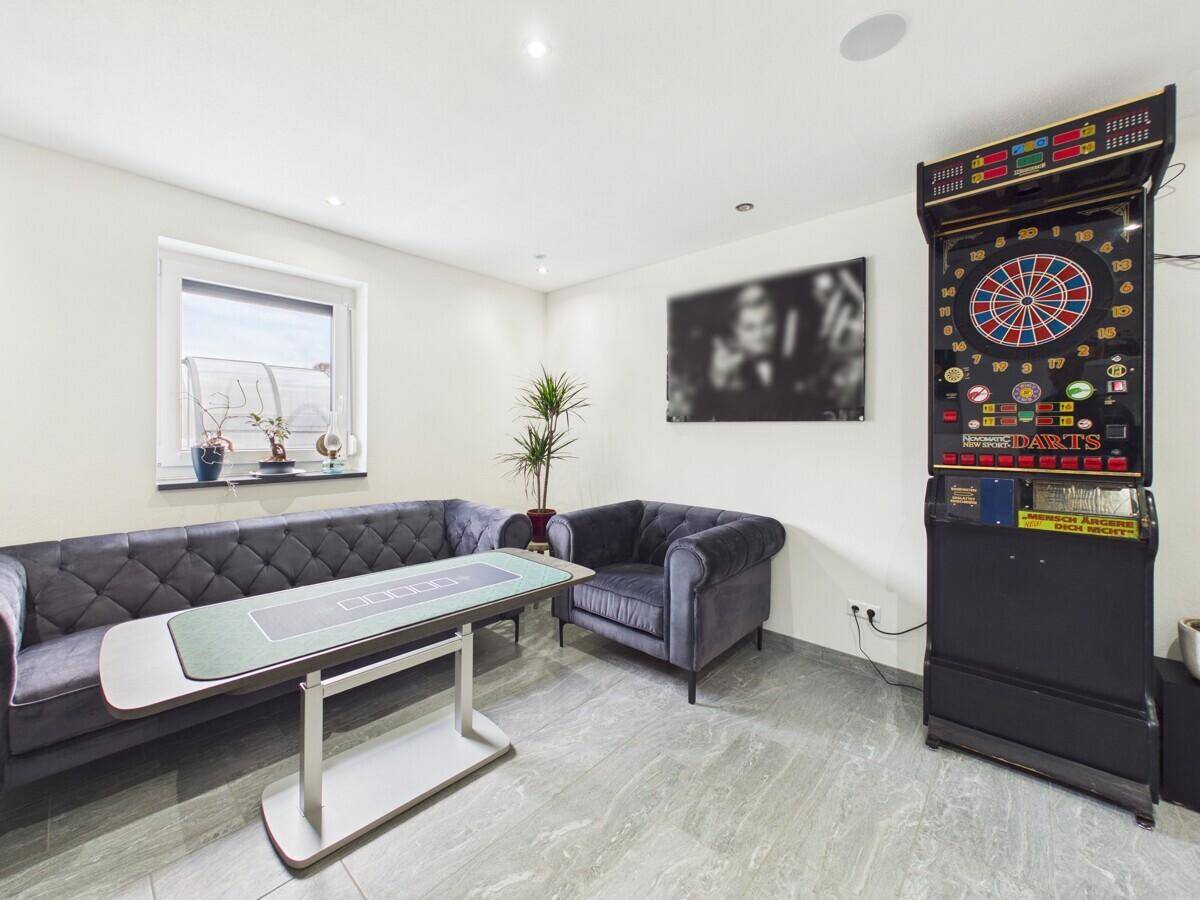Spielzimmer mit Dartscheibe, Sofa und Tisch für Unterhaltungszwecke.