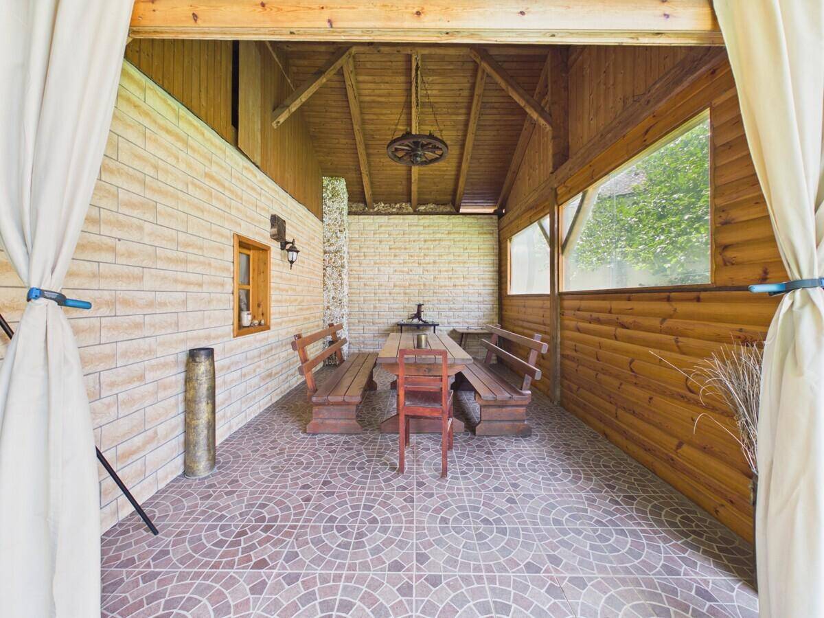 Geräumige überdachte Terrasse mit Holzbänken und einem großen Tisch, ideal für Geselligkeit.