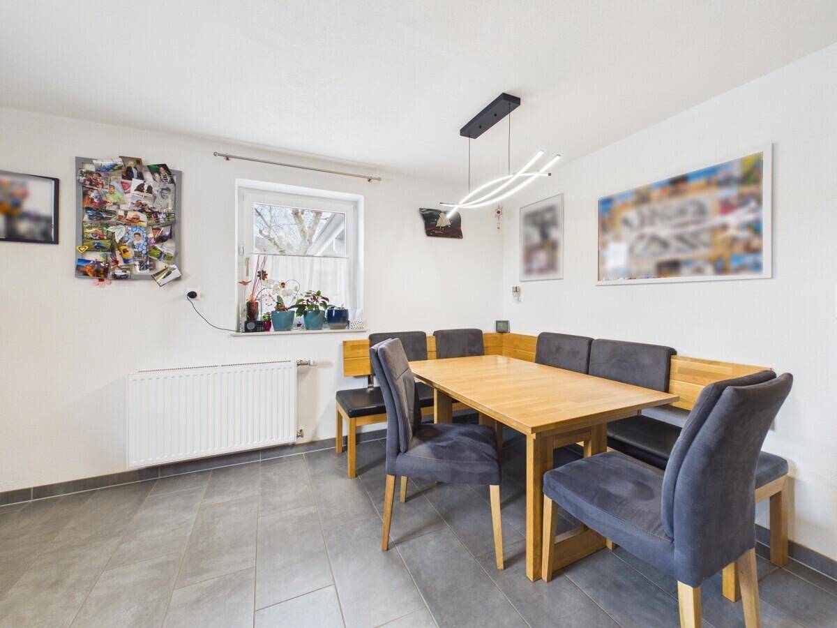 Gemütlicher Essbereich mit Holztisch, Eckbank und modernen Fliesenboden.