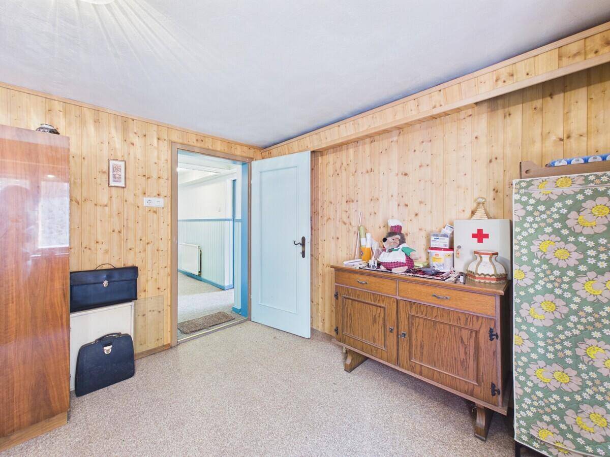 Einfaches Schlafzimmer mit Holzvertäfelung, Teppichboden und Blick auf den Flur.