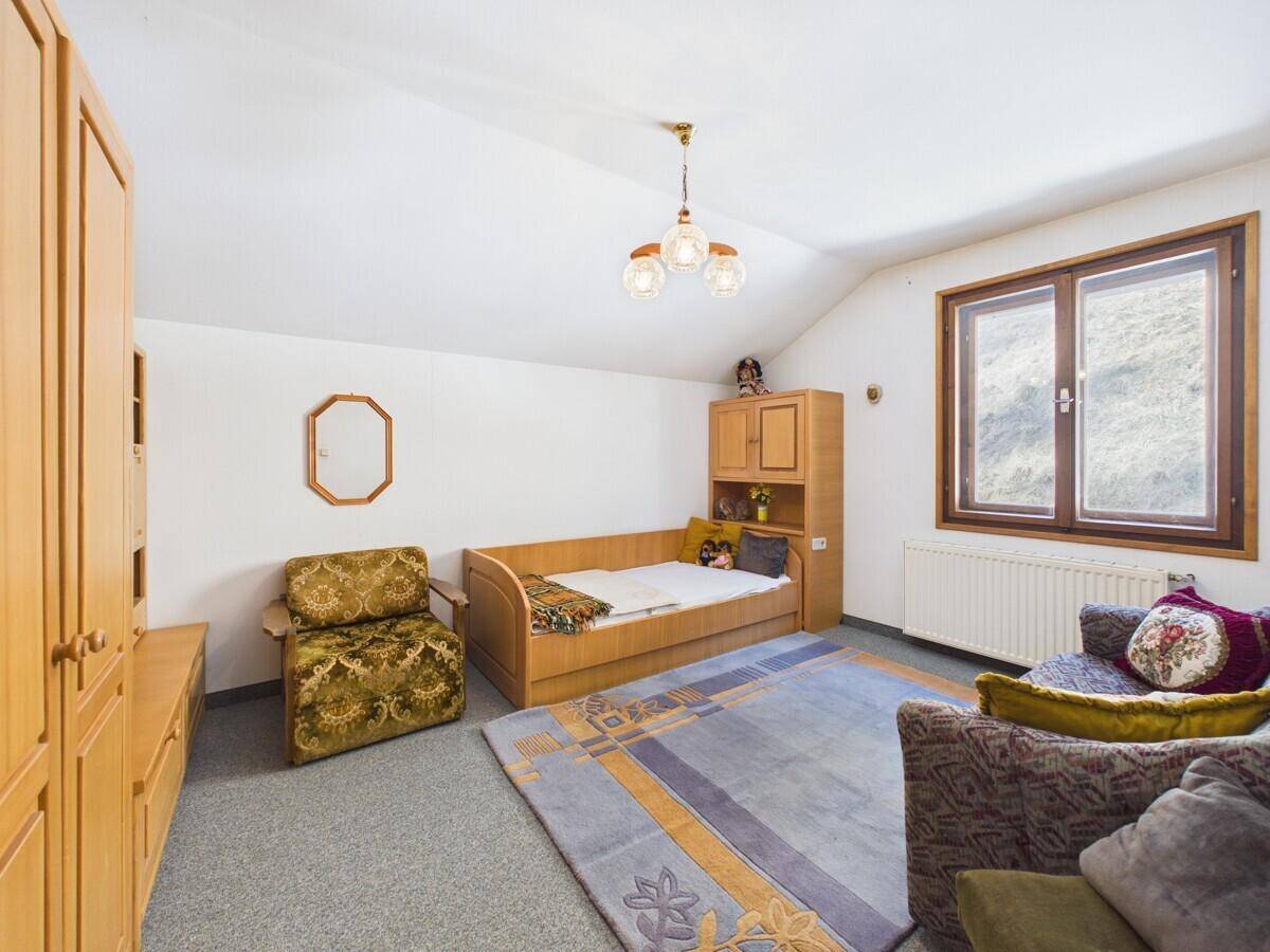 Gemütliches Schlafzimmer im Dachgeschoss mit Teppichboden, Holzmöbeln und schrägen Decken.