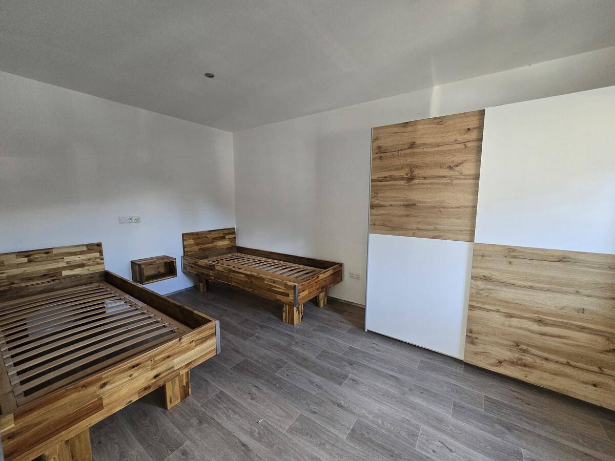 Schlafzimmer mit zwei Holzbetten, Holzboden und einem großen Dachfenster für viel Tageslicht.