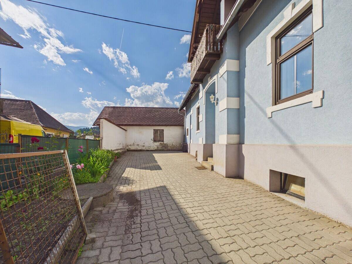 Außenansicht des Hauses mit gepflasterter Fläche und einem kleinen Gartenbereich.