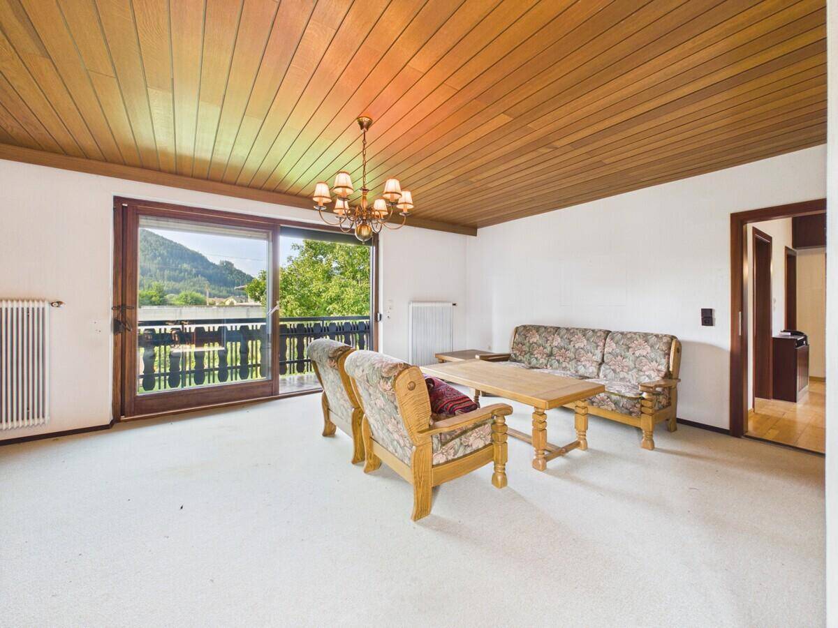 Wohnzimmer mit Teppichboden, Holzdecke und Zugang zu einem Balkon mit Bergblick.