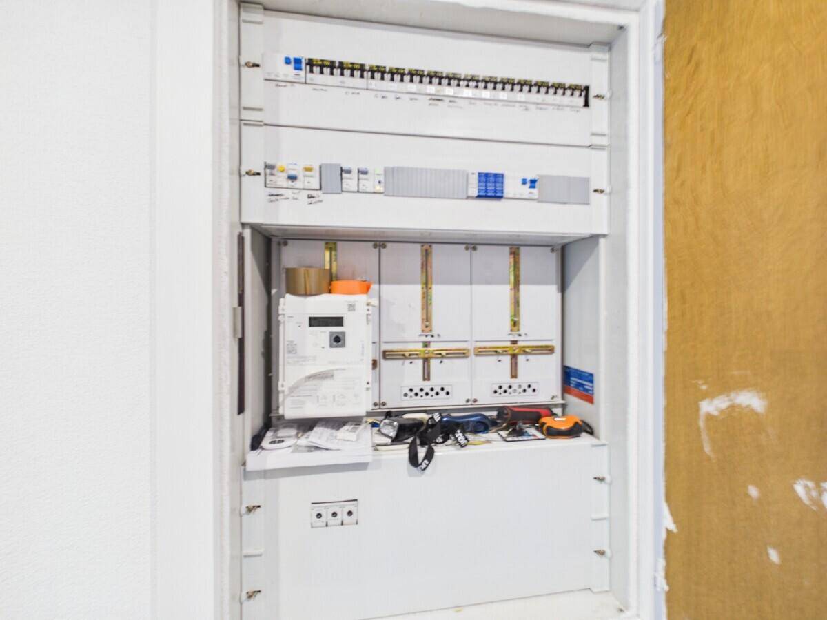 Offener Sicherungskasten mit Zähler und verschiedenen elektrischen Komponenten.