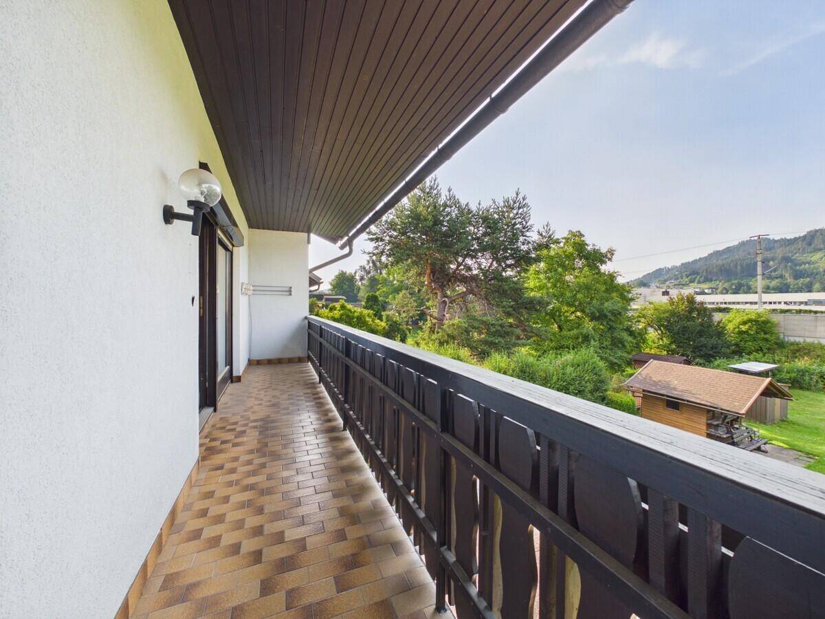 Langer Balkon mit Fliesenboden und traditionellem Holzgeländer, bietet weite Aussicht.