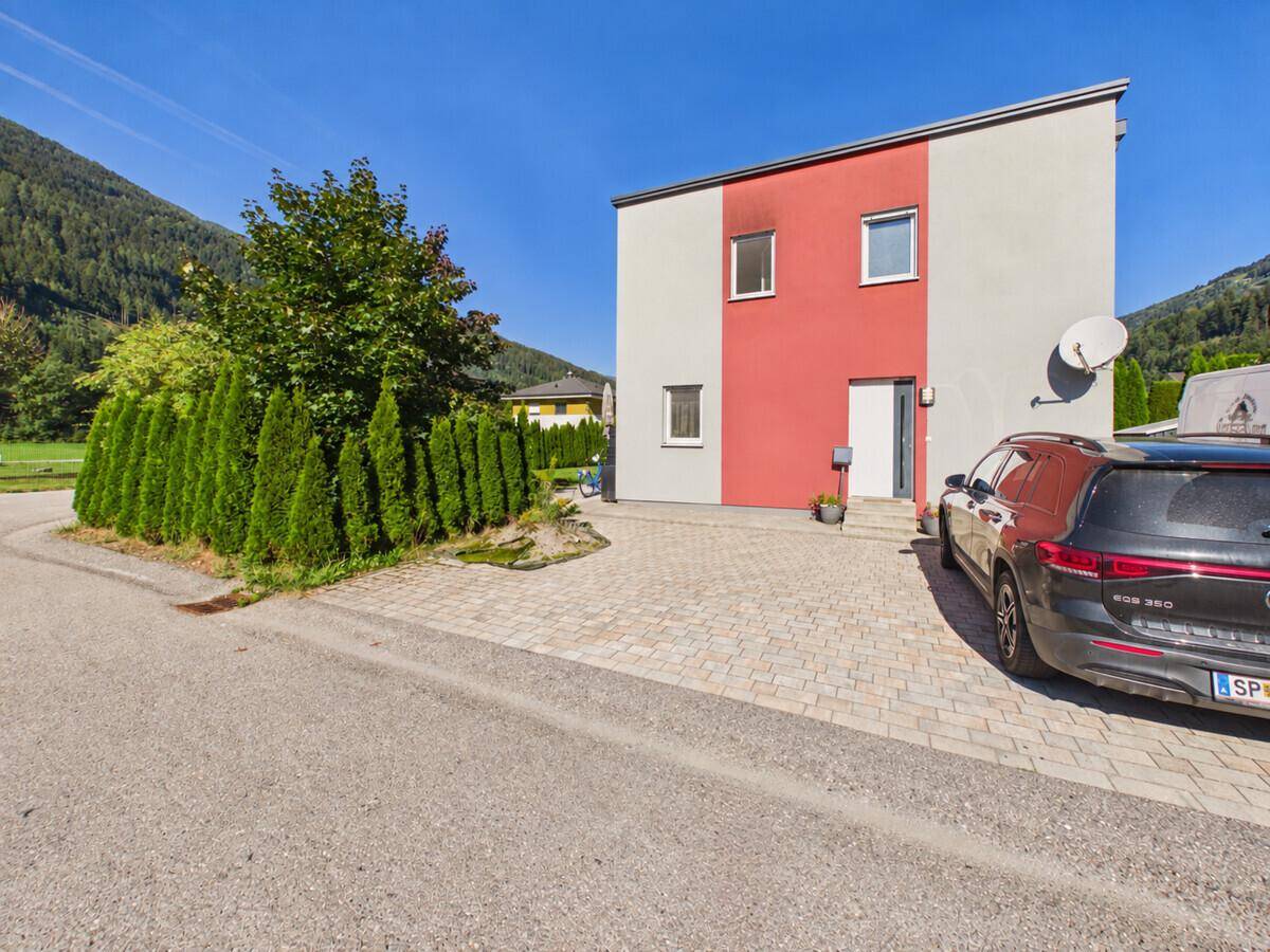 Vorderansicht des modernen Hauses mit gepflasterter Einfahrt und geparktem Auto.