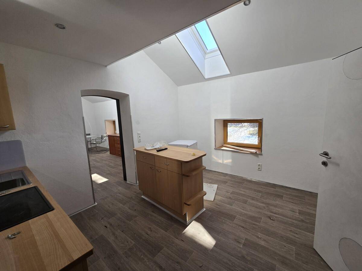 Kompakte Küche mit Holzarbeitsplatte, Induktionskochfeld und Dachfenster, das viel Licht spendet.