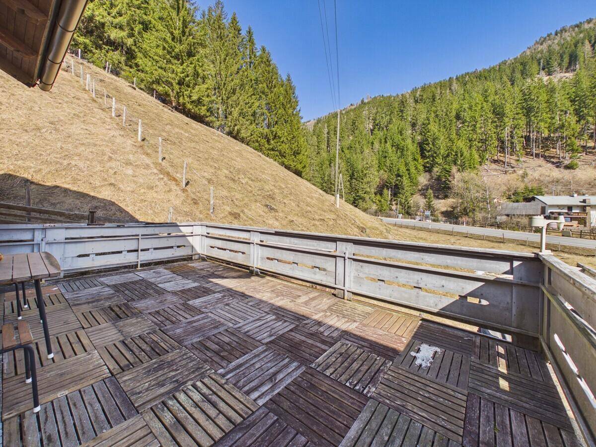 Großer Holzbalkon mit Holzdielen und weitem Blick auf die umliegende Berglandschaft.