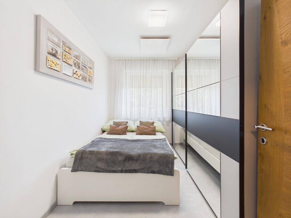 Gemütliches Schlafzimmer mit Einzelbett und großem Spiegelschrank.